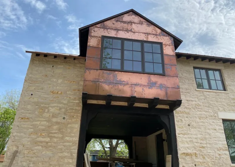 Copper metal panel facade on a stone building for Skylight Installation in Three Lakes